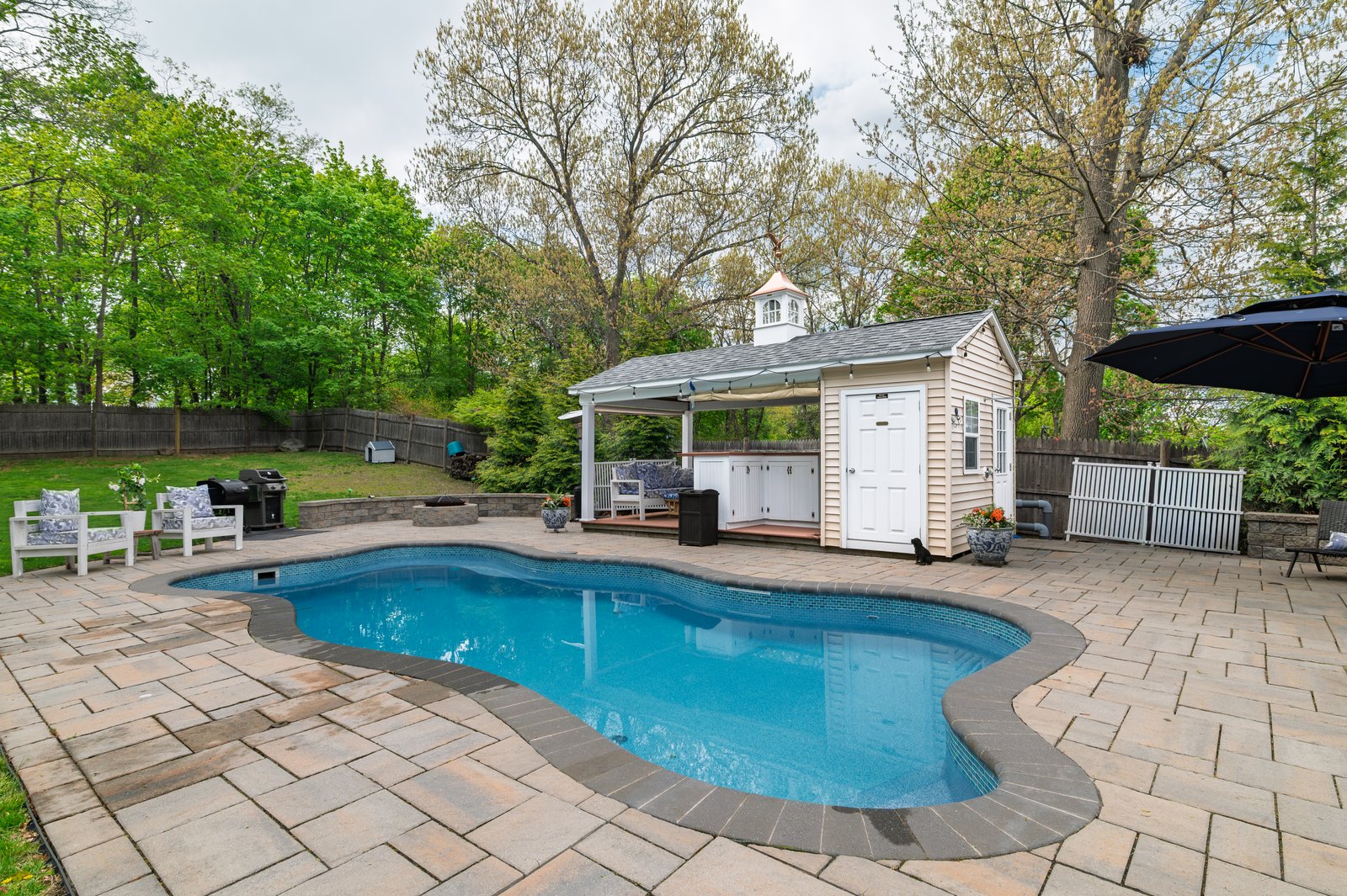 Wide daytime view of the backyard with the heated saltwater pool and covered pavilion at 51 Faxon Street